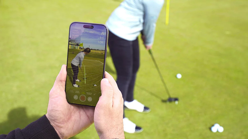 A coach using the PuttView app on iPhone to analyse a student's putt